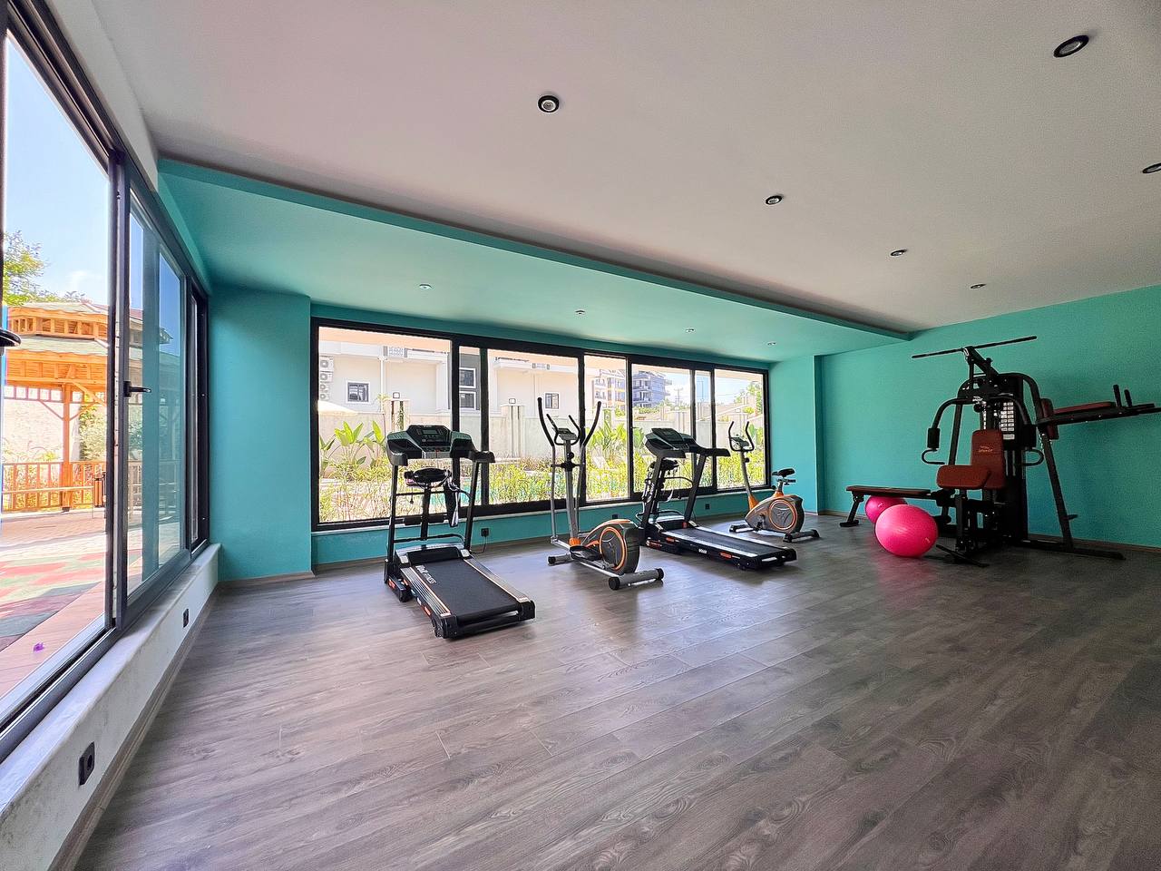 Daire sakinleri için spor salonunda koşu bantları, kürek ergometresi ve turkuaz duvarlar