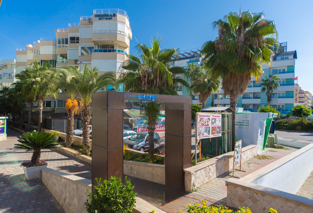 Türkiye’de Alanya’daki rezidansın girişinde taş saksılı palmiyeler ve döşeli yürüyüş yolu