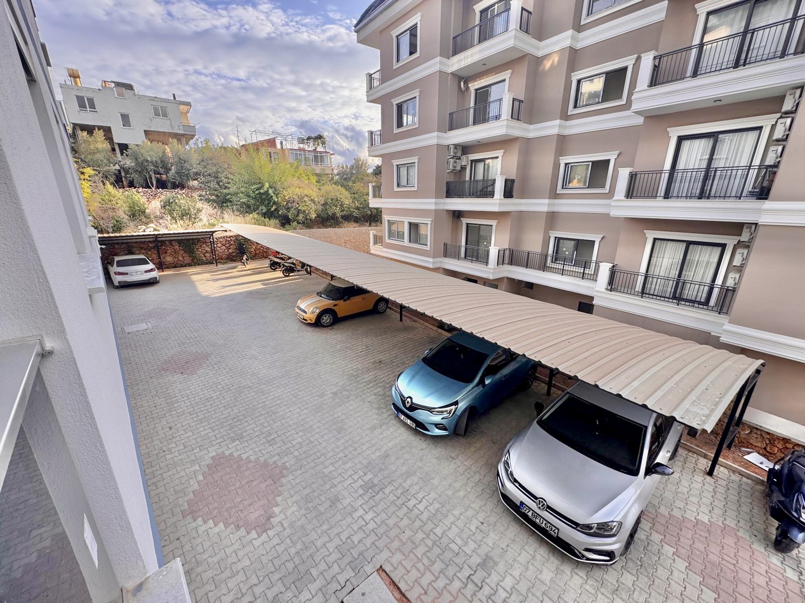 Kemerli metal sundurmalı otoparkta, Alanya'daki dairelerin yer aldığı sitenin yeşil yamacı