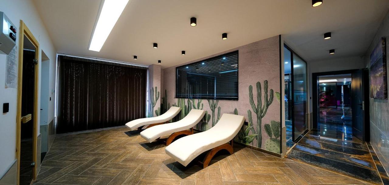 Spa area with three curved white loungers, cactus wall art, and dark tiled flooring