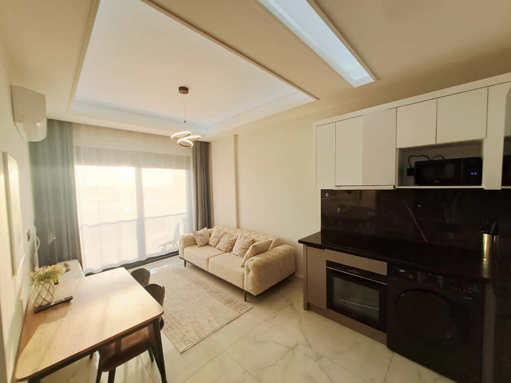 Kitchen-living room with a light sofa and marble counter in an apartment for sale in Turkey