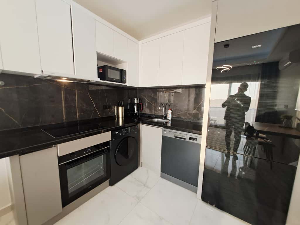 Kitchen with white cabinets, black marble counters, and built-in appliances