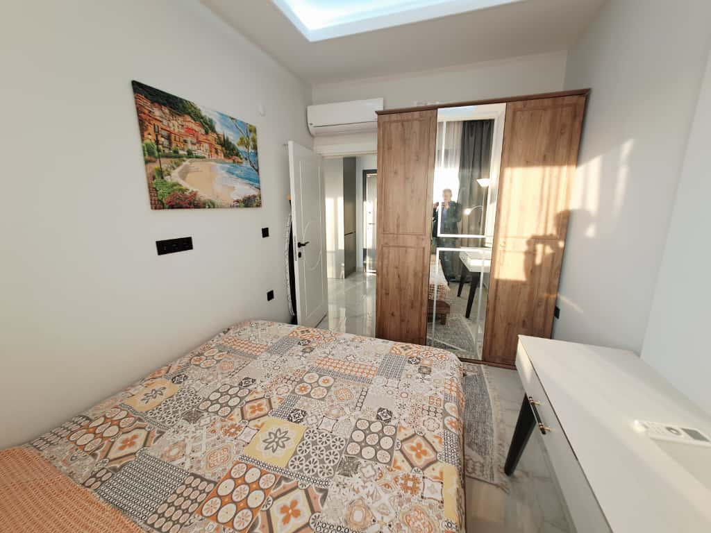 Bedroom with a patterned bedspread, mirrored wardrobe, and white vanity table in Alanya
