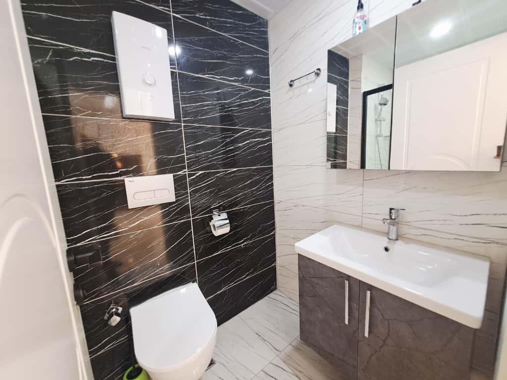 Bathroom with a white basin, gray vanity, and contrasting veined tiles in a 1+1 apartment