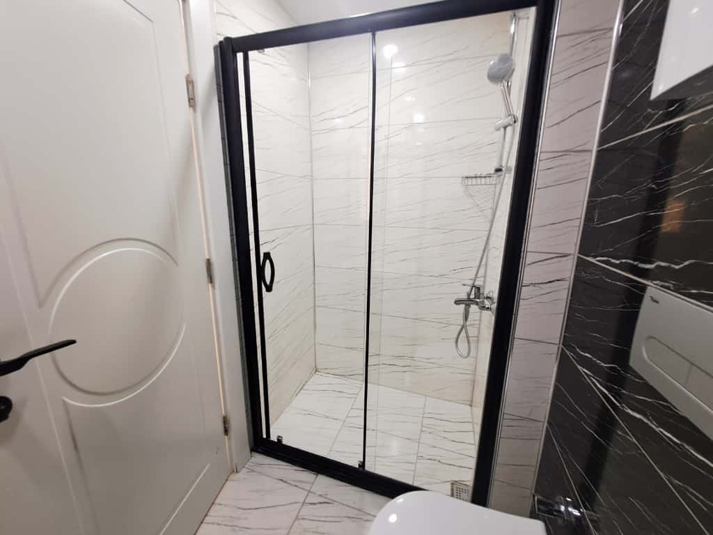 Bathroom with a black-framed shower enclosure and clear sliding doors in a flat in Oba