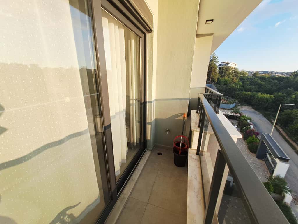Narrow balcony with beige tile, clear black-framed railing, and road views at a property for sale