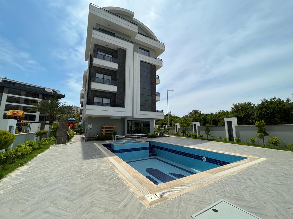 Empty blue-tiled pool beside the balcony facade in a complex where apartments are for sale in Turkey
