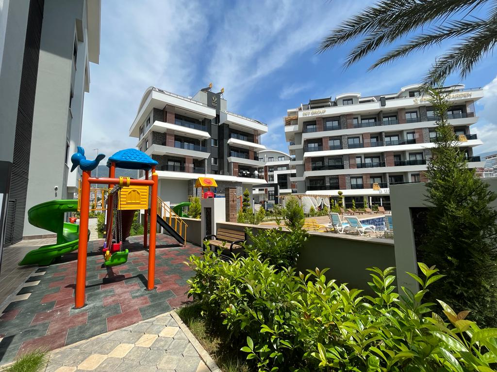 Playground with a green spiral slide beside the pool in a complex where apartments are for sale in Turkey