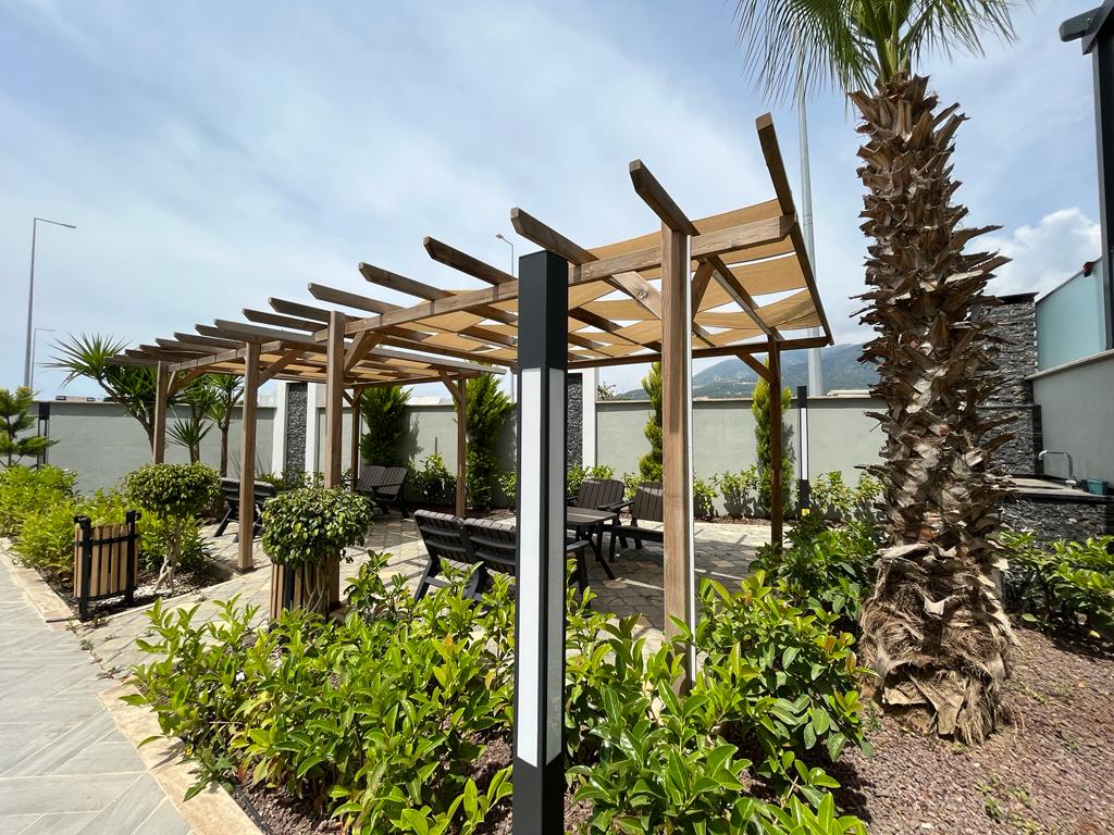 Relaxation area with wooden pergolas and tables on the grounds of a residence in Oba, where homes are for sale