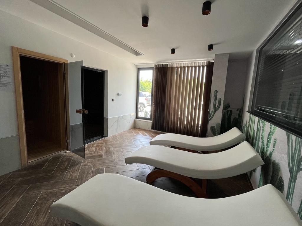 Spa area with curved white loungers by a window with blinds in a complex with flats in Alanya