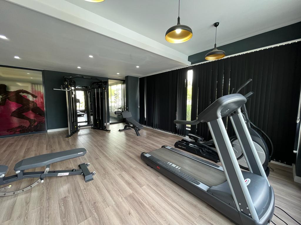 Gym with a foreground treadmill and strength station by a mirrored wall for flat residents