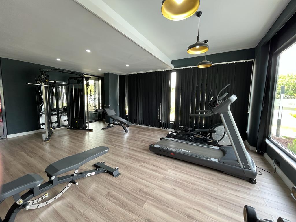 Gym with a treadmill by the window and an adjustable bench in a complex with homes in Alanya