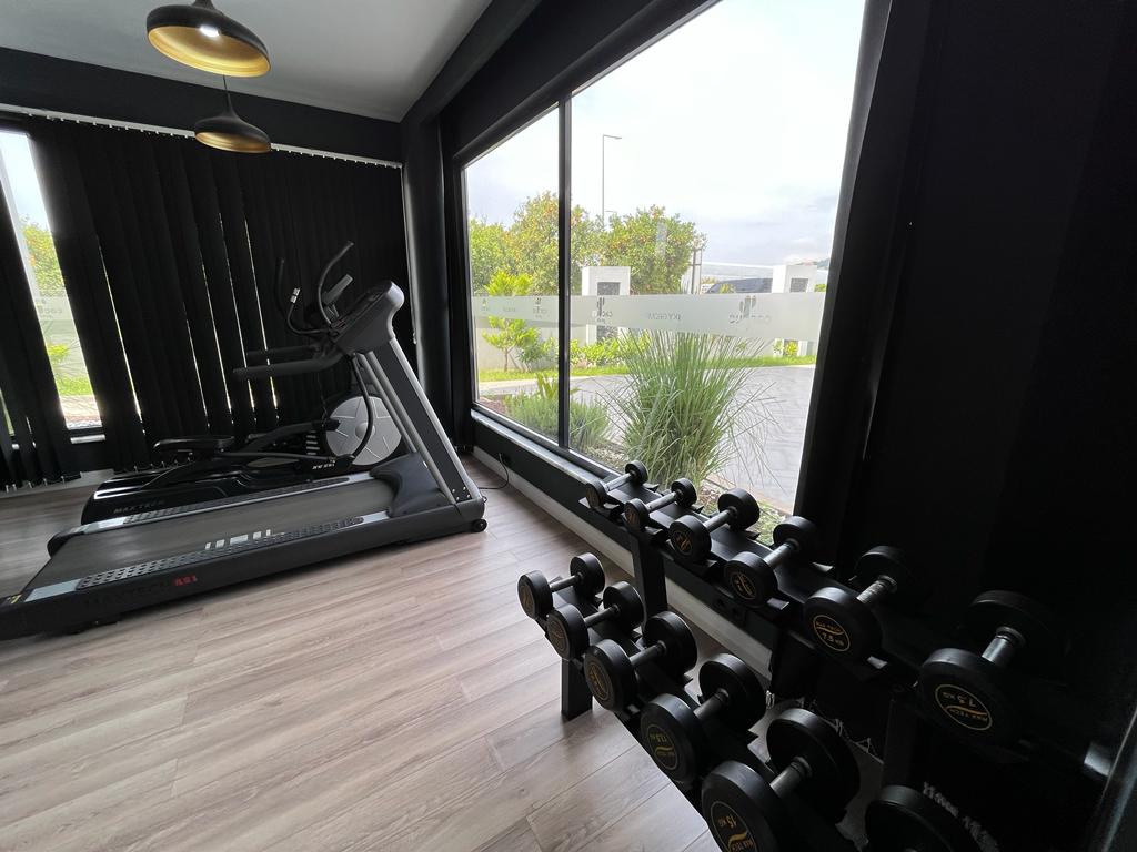Gym with a dumbbell rack, treadmill, and elliptical trainer beside panoramic windows