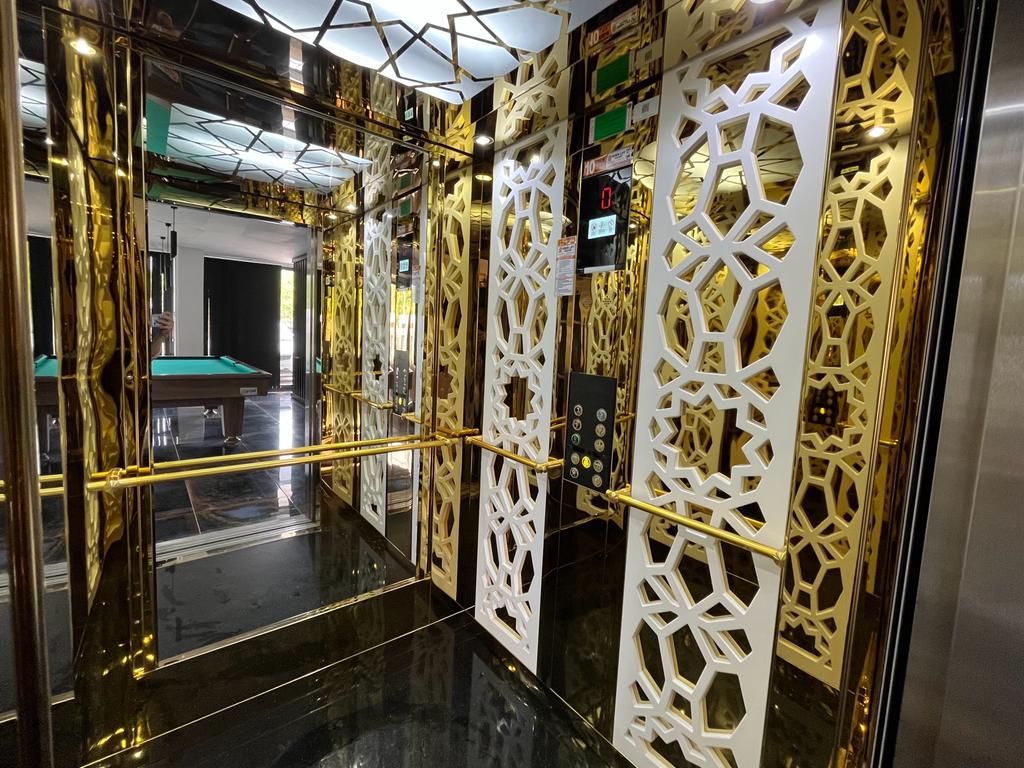Elevator with mirrored walls, gold-toned panels, and geometric grilles in a complex with apartments in Oba