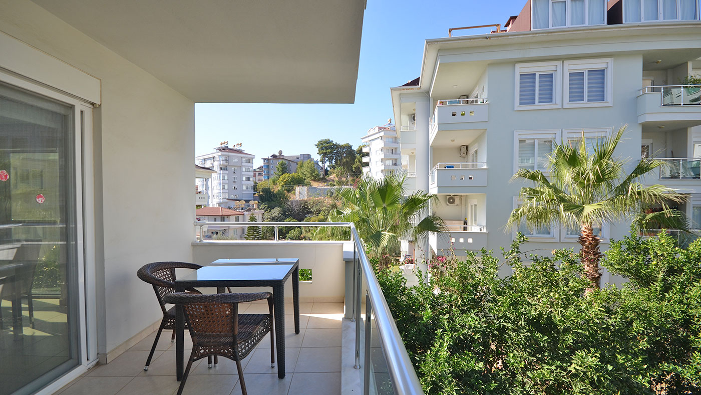 Palmiyeler arasında dar balkon, masa ve iki hasır sandalye ile Türkiye’de