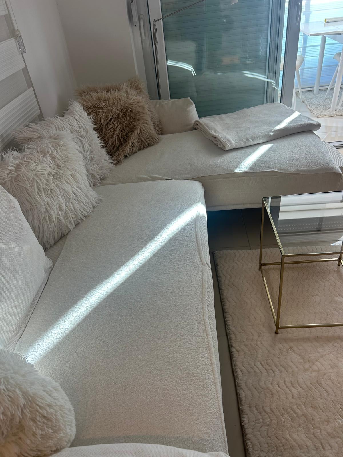 Panoramik camlı aydınlık salon, satılık konutta açık renk koltuk ve halıyla