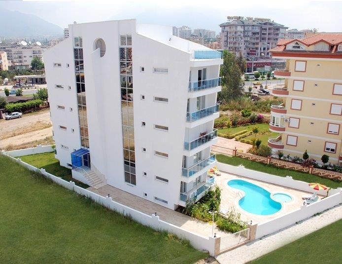 Avludaki kıvrımlı havuzlu beyaz apartman: Oba, Alanya’da satılık 1+1 daire, Türkiye — New Level Group