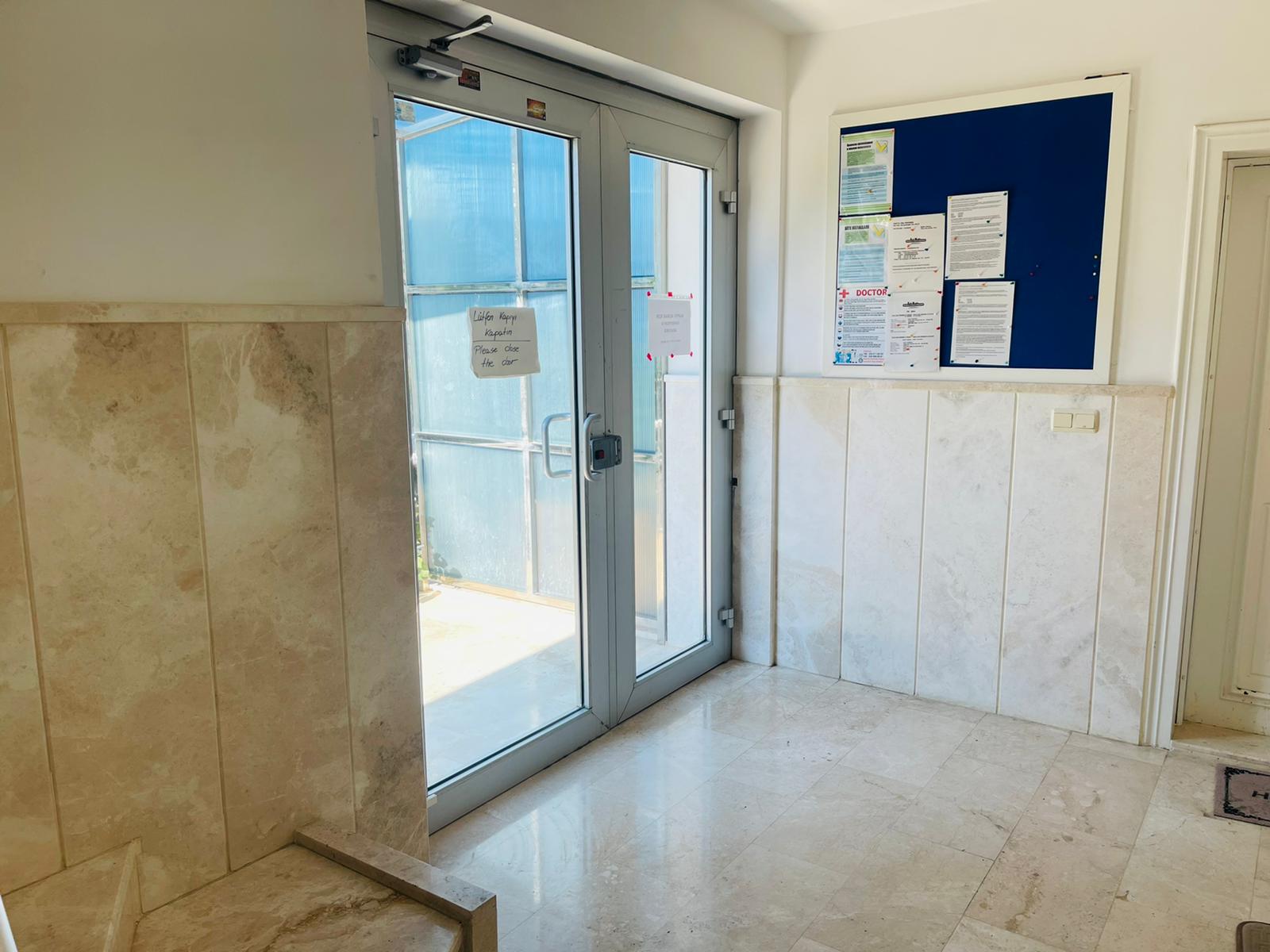 Mermer kaplamalı vestibül, satışta olan yapının cam giriş kapısı ve dış çıkışıyla