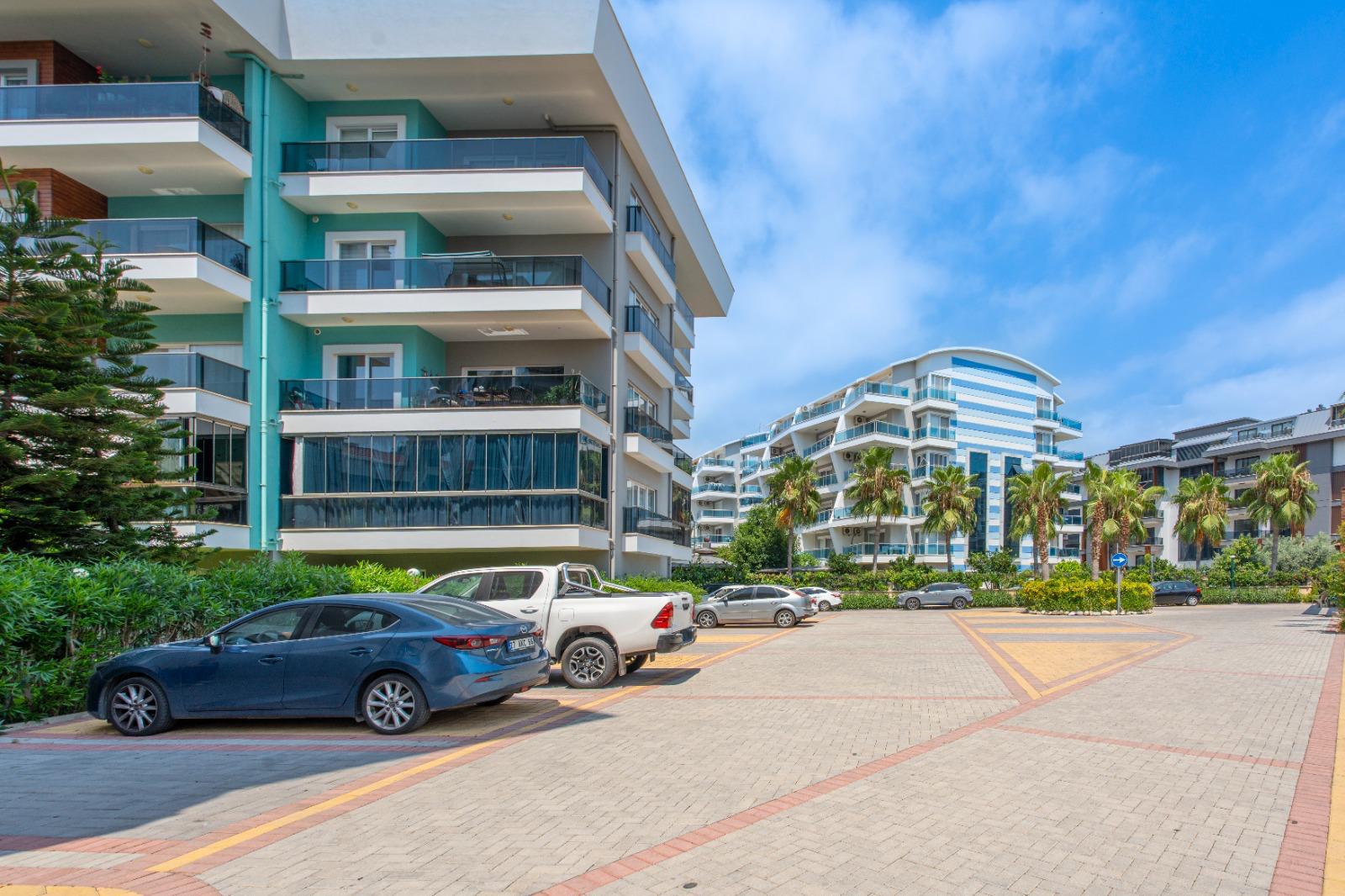 Palmiyeli açık otopark ve balkonlu konut binaları Oba'da