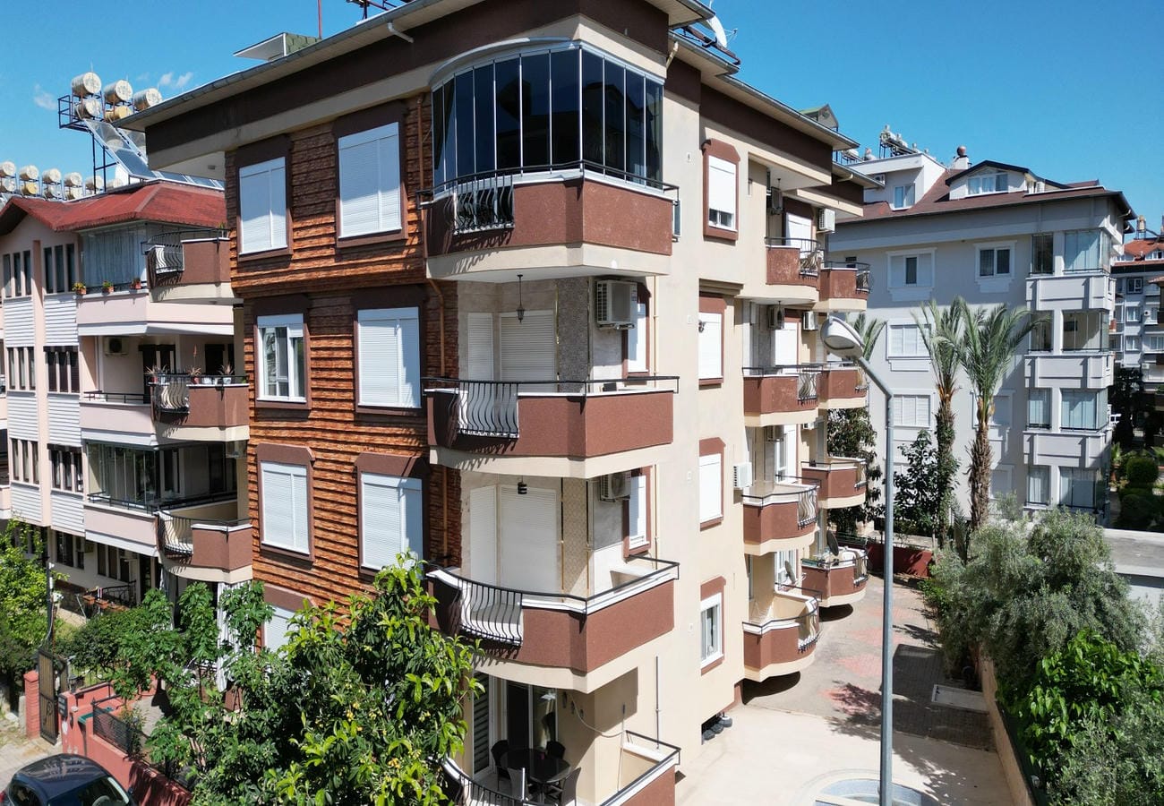 Kahverengi ahşap kaplamalı çok katlı konut binası, kapalı locası ve balkonlarıyla satılık daire barındırıyor