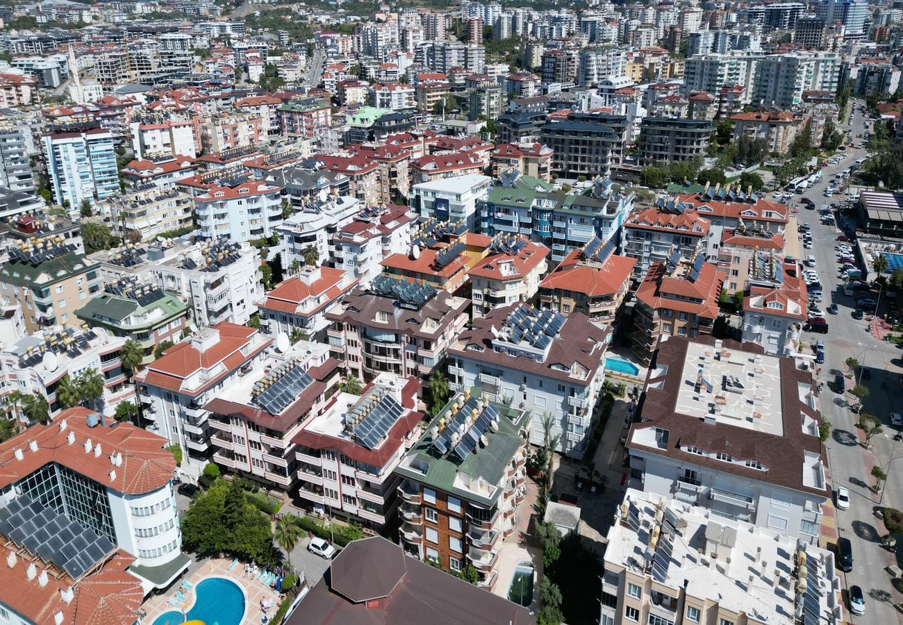 Oba’daki konutların bulunduğu şehir manzarasında kırmızı çatılar ve alçak bölümde açık havuz görülüyor