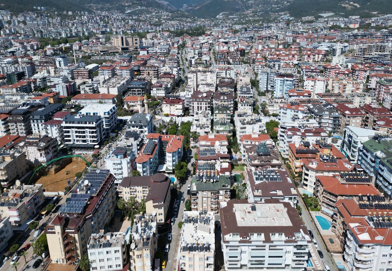 Dağ yamacının ardındaki yoğun şehir dokusu ve açık havuz Oba’dan panoramik bir görünüm sunuyor