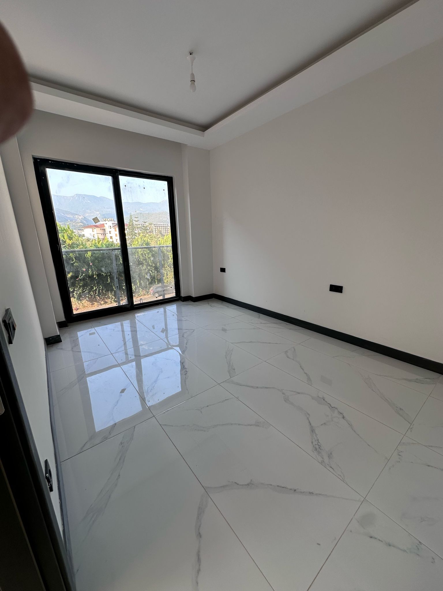 Boş yatak odası, panoramik cam kapısı ve dağ manzarasıyla Oba’daki dairede