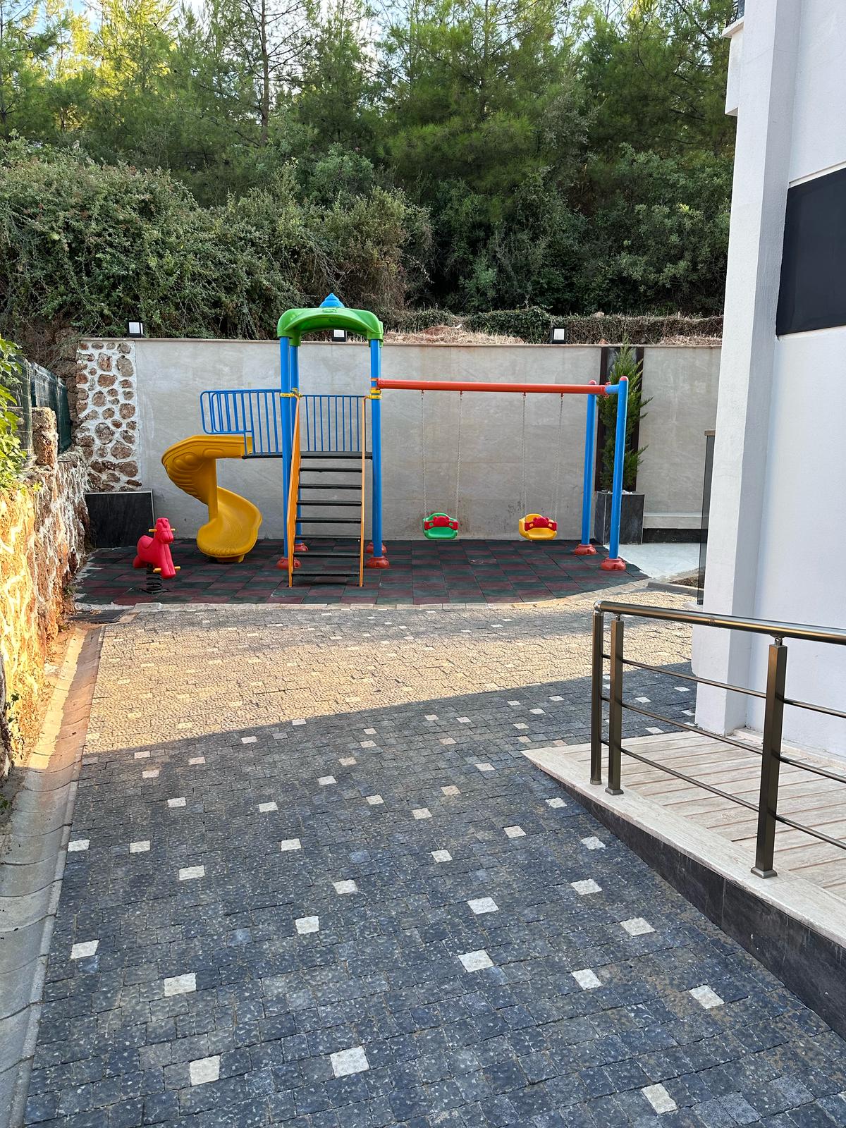 Çocuk oyun alanı, kaydırak ve renkli yaylı salıncaklarla satışın sürdüğü sitede