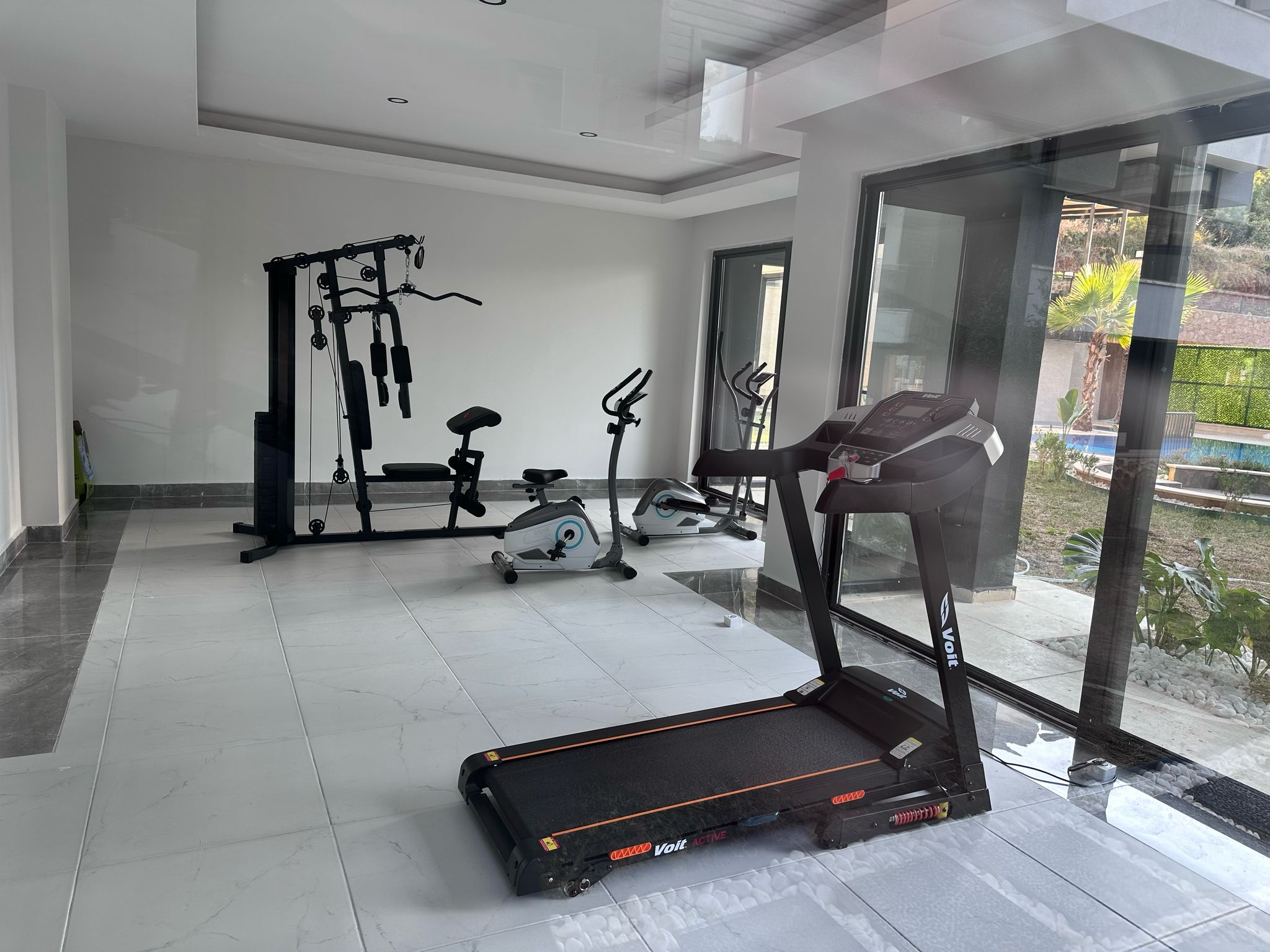 Koşu bandı ve iki bisiklet, daire sakinlerine ayrılmış spor salonunda panoramik pencerenin önünde