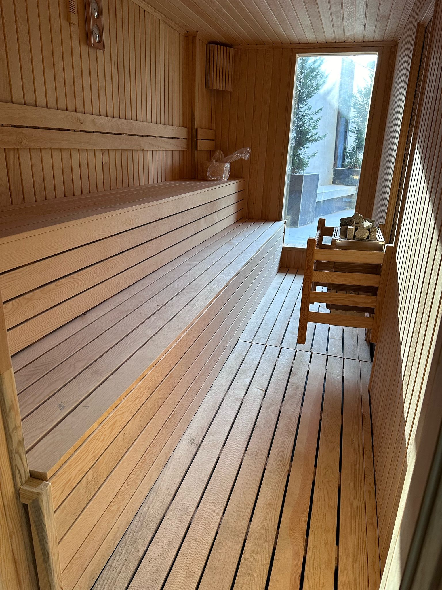 Ahşap raflı sauna ve köşedeki taşlı soba, Oba’daki dairelerin bulunduğu rezidansın spa alanında