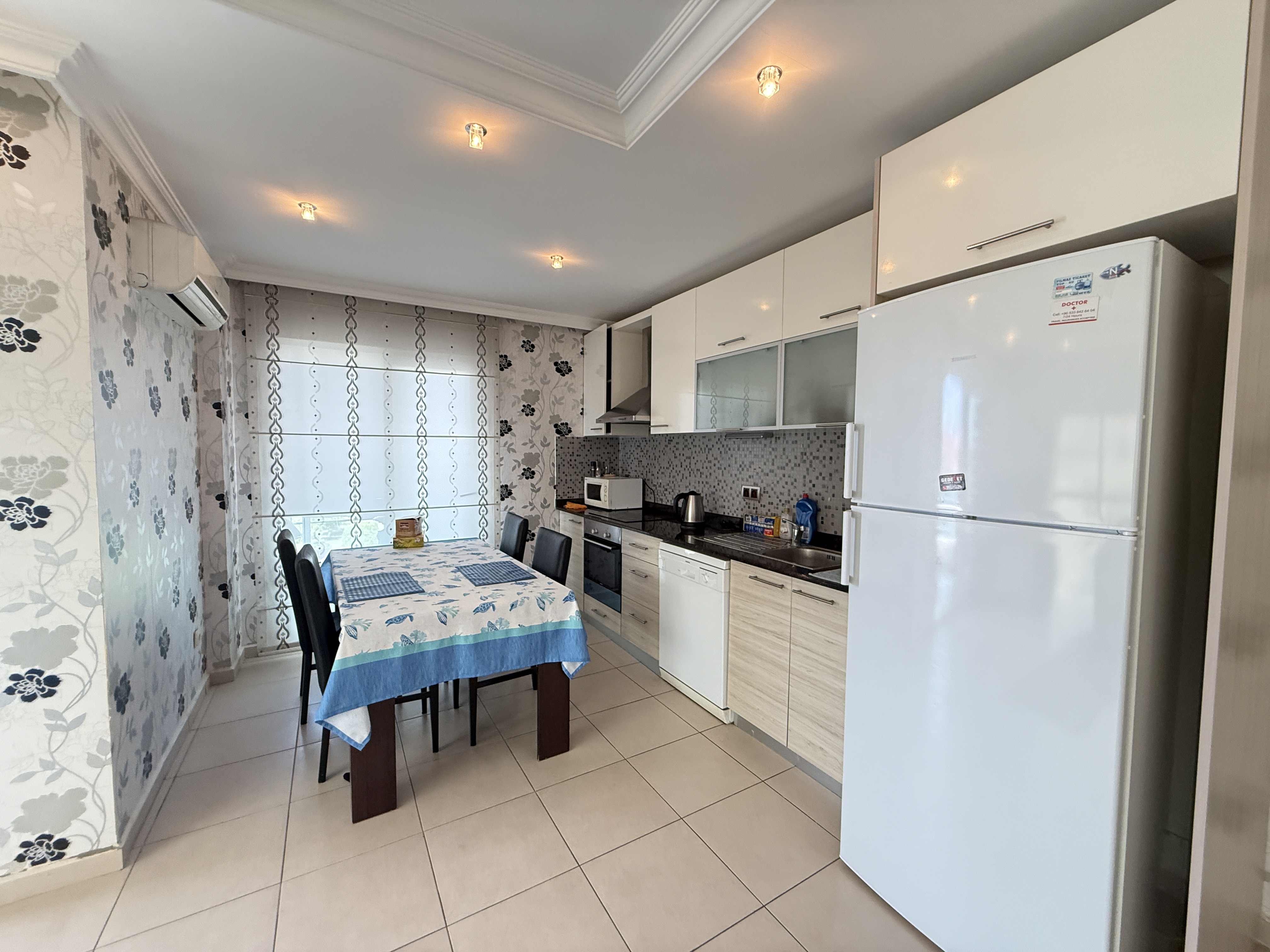 Beyaz mutfak dolapları ve mozaik backsplash, Oba’daki konutun mutfağında