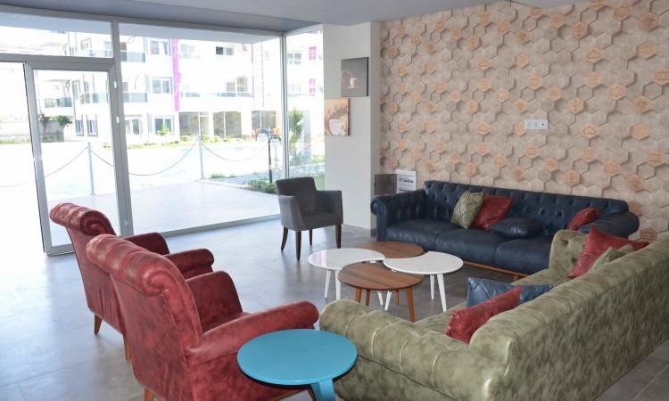 Panoramik camlı lobi, yeşil köşe kanepe ve kırmızı koltuklarla Kestel’deki dairelerin bulunduğu komplekste