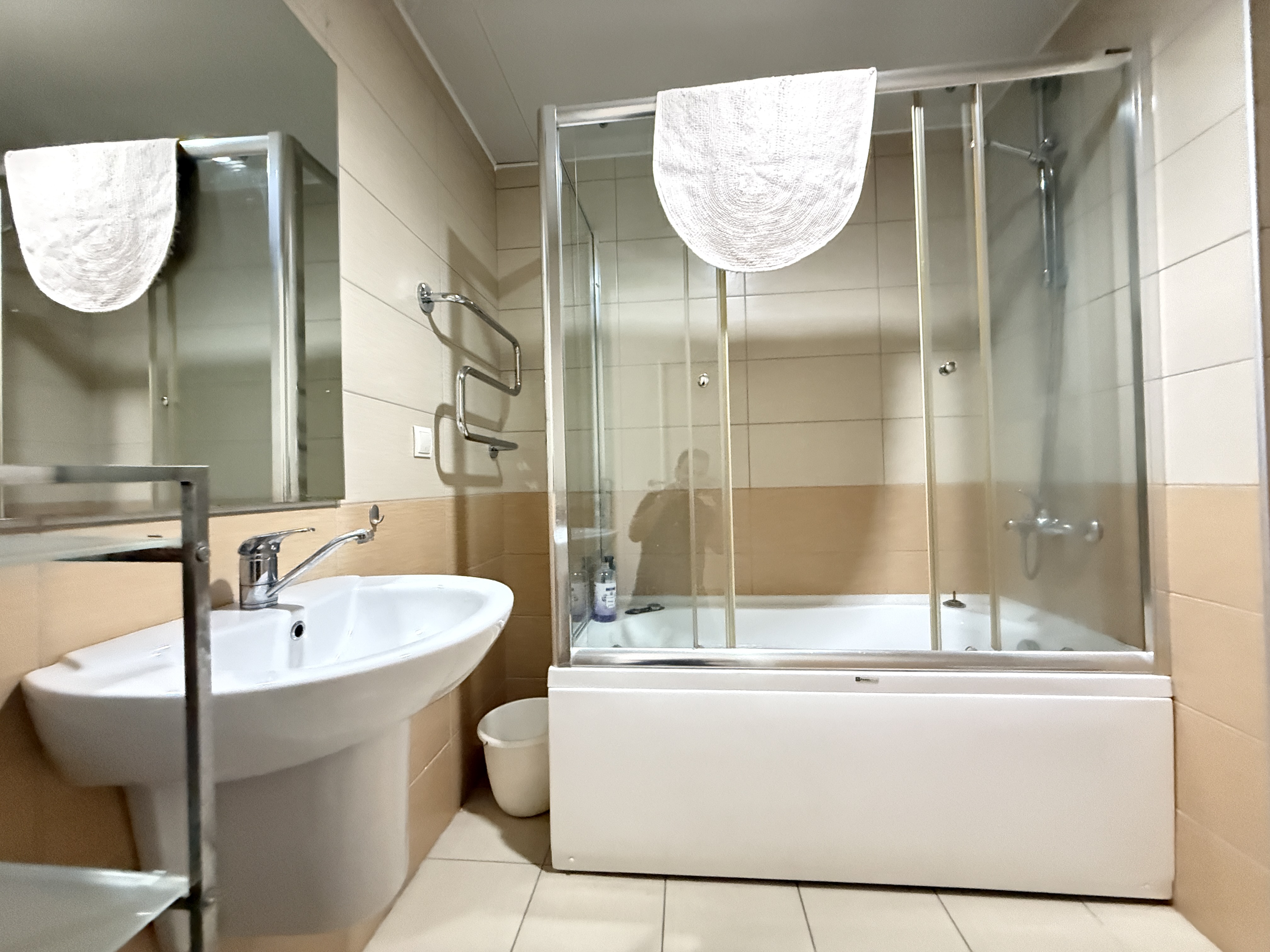Küvet, cam perde ve beyaz lavabo bulunan banyo, Oba’daki konutta