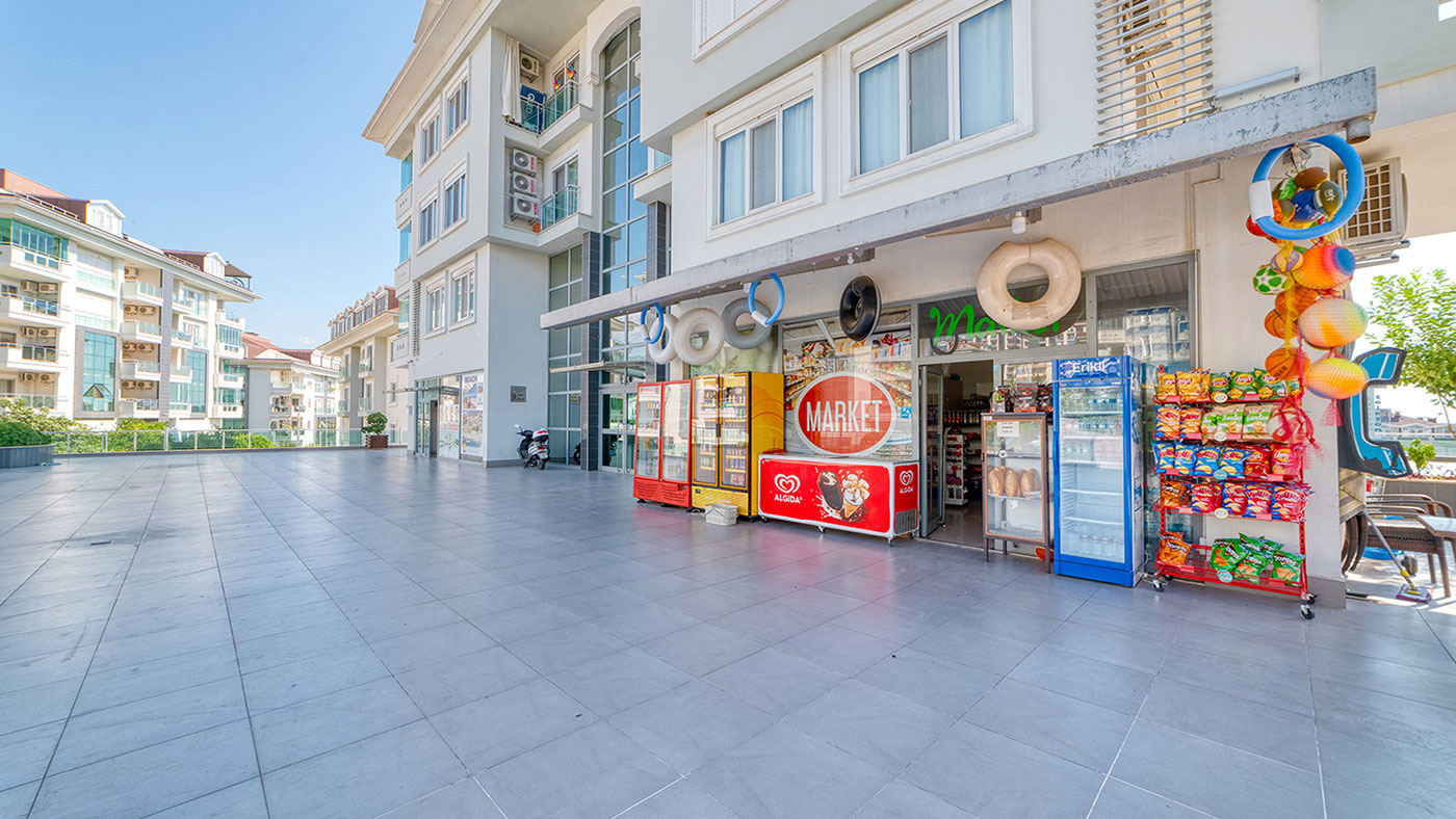 İçecek dolapları ve ürün vitrini bulunan mağaza terası, Türkiye’deki konut kompleksinde