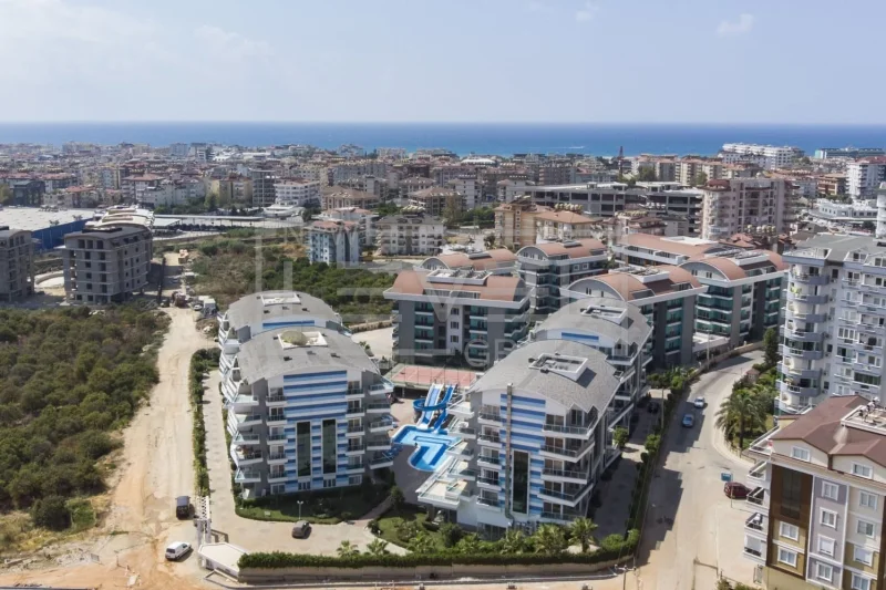 Yüksekten görülen merkezi havuzlu konut kompleksi, Oba'da satılık rezidans ve ufukta deniz çizgisiyle