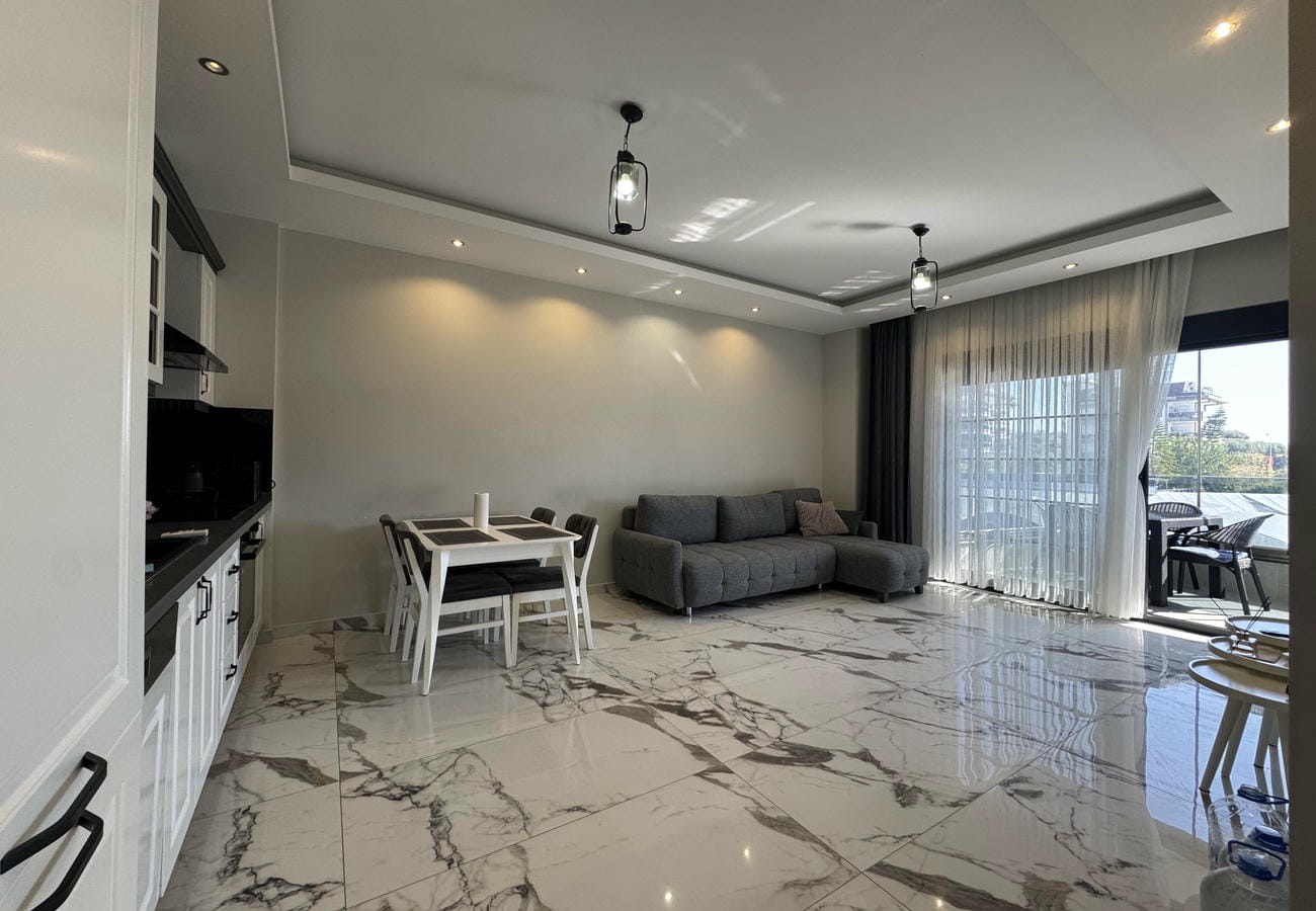 Gri köşe koltuklu mutfak salon Türkiye'deki dairede beyaz mutfak ve panoramik pencereyle