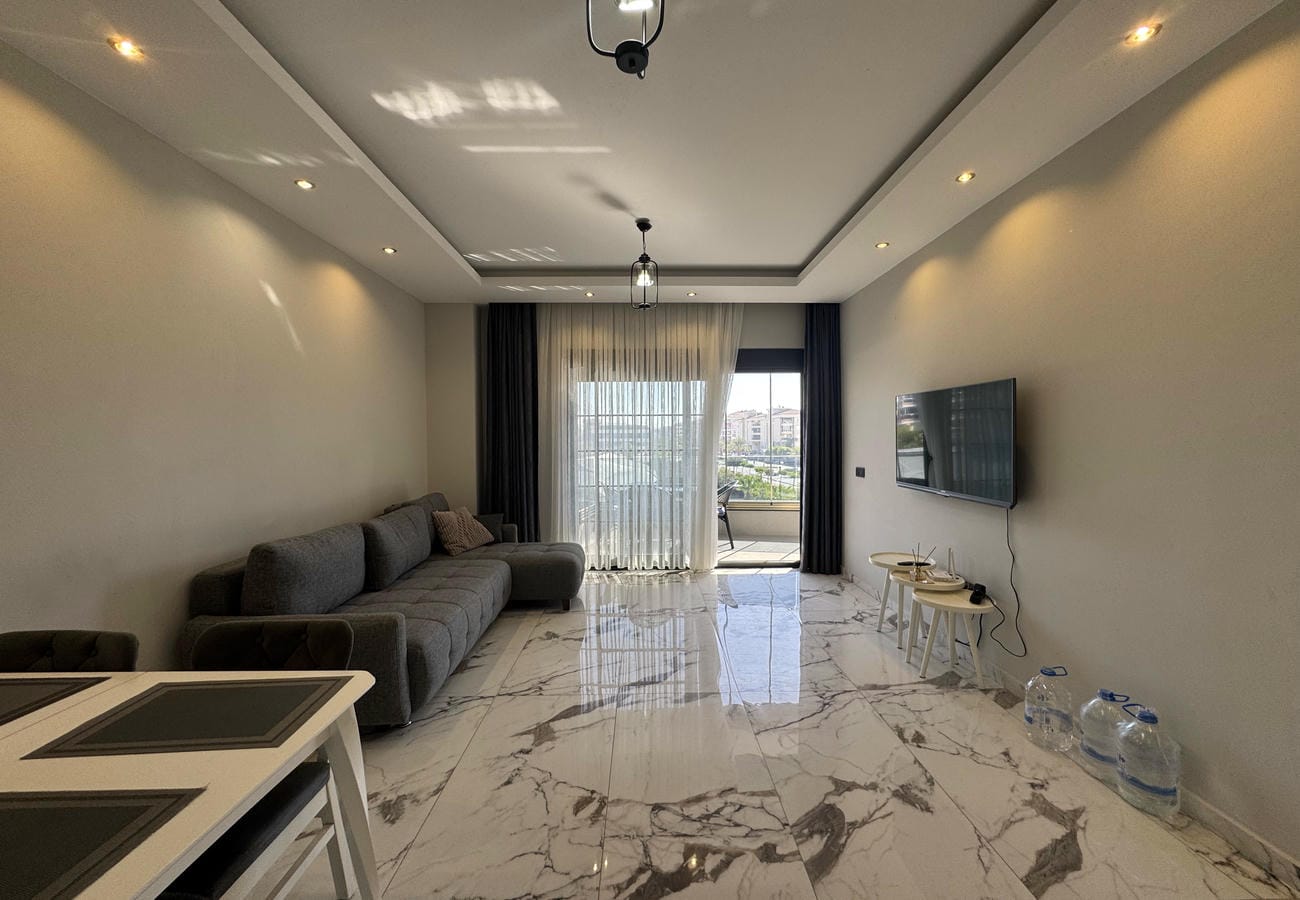 Gri köşe koltuklu salon Kestel'de dairede televizyon ve panoramik balkon camlarıyla