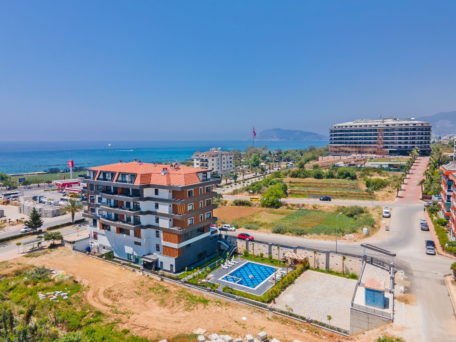 Açık havuzlu konut kompleksi ve arka planda deniz Türkiye'de satılık daireleri gösteriyor