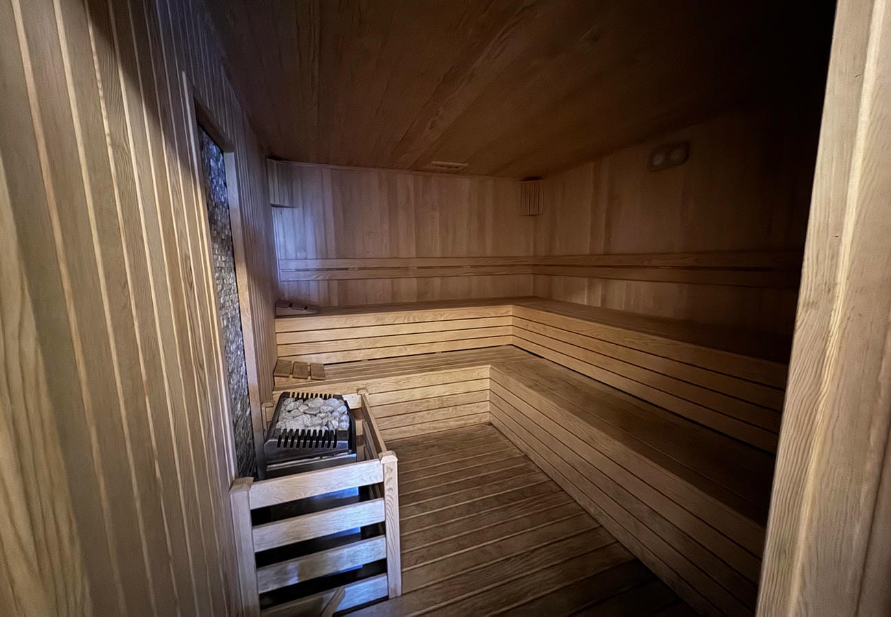 Ahşap raflı sauna taşlı elektrikli soba ve dar pencereyle sade biçimde düzenlenmiş