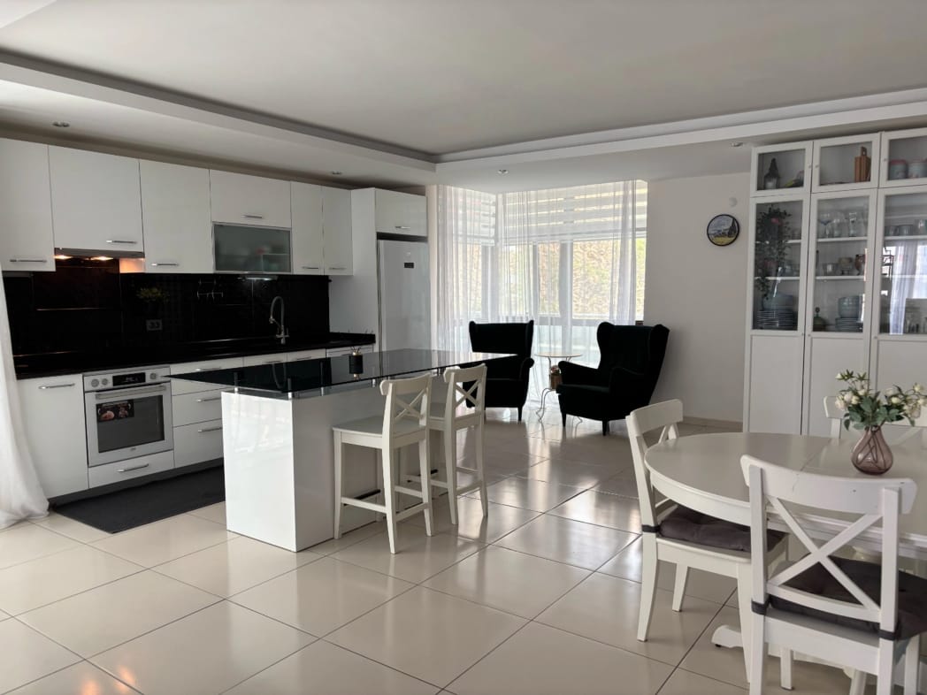Beyaz mutfaklı mutfak salonunda ada ve panoramik pencere, daire içinde
