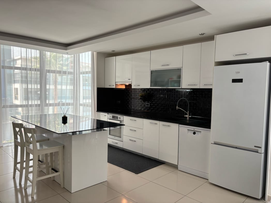 Beyaz mutfaklı mutfak salonunda ada ve panoramik camlar, konutun içinde