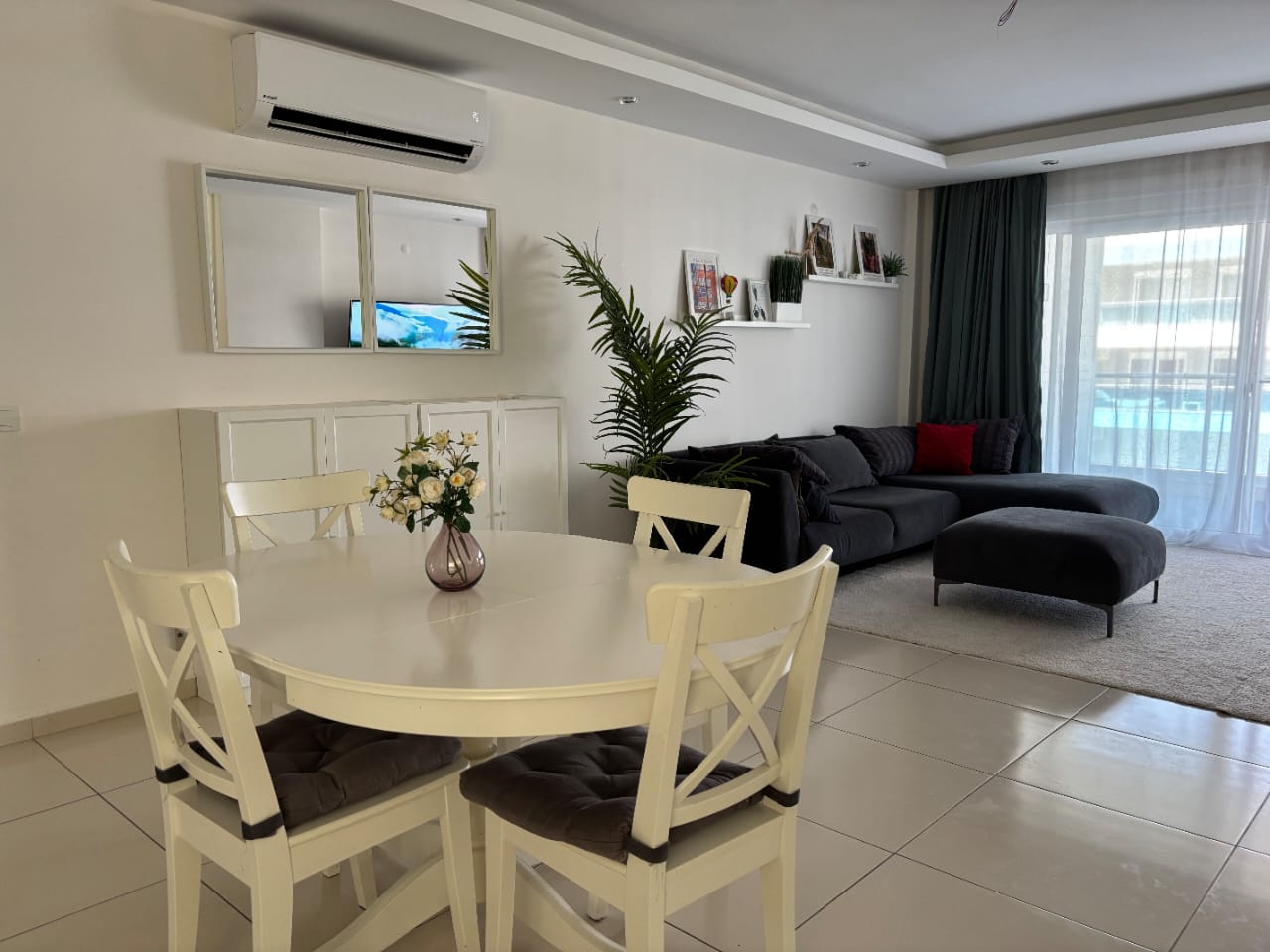 Koyu gri köşe koltuklu salonda yemek masası ve panoramik pencere, satılık konut içinde
