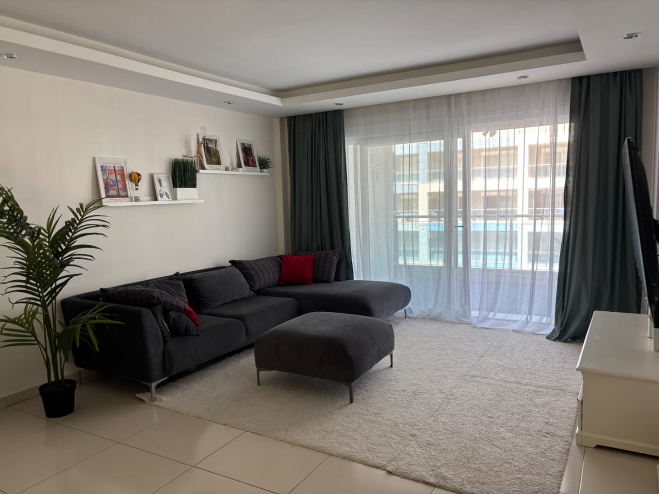 Koyu gri koltuklu salonda puf ve panoramik pencere, Türkiye’de satılık dairede