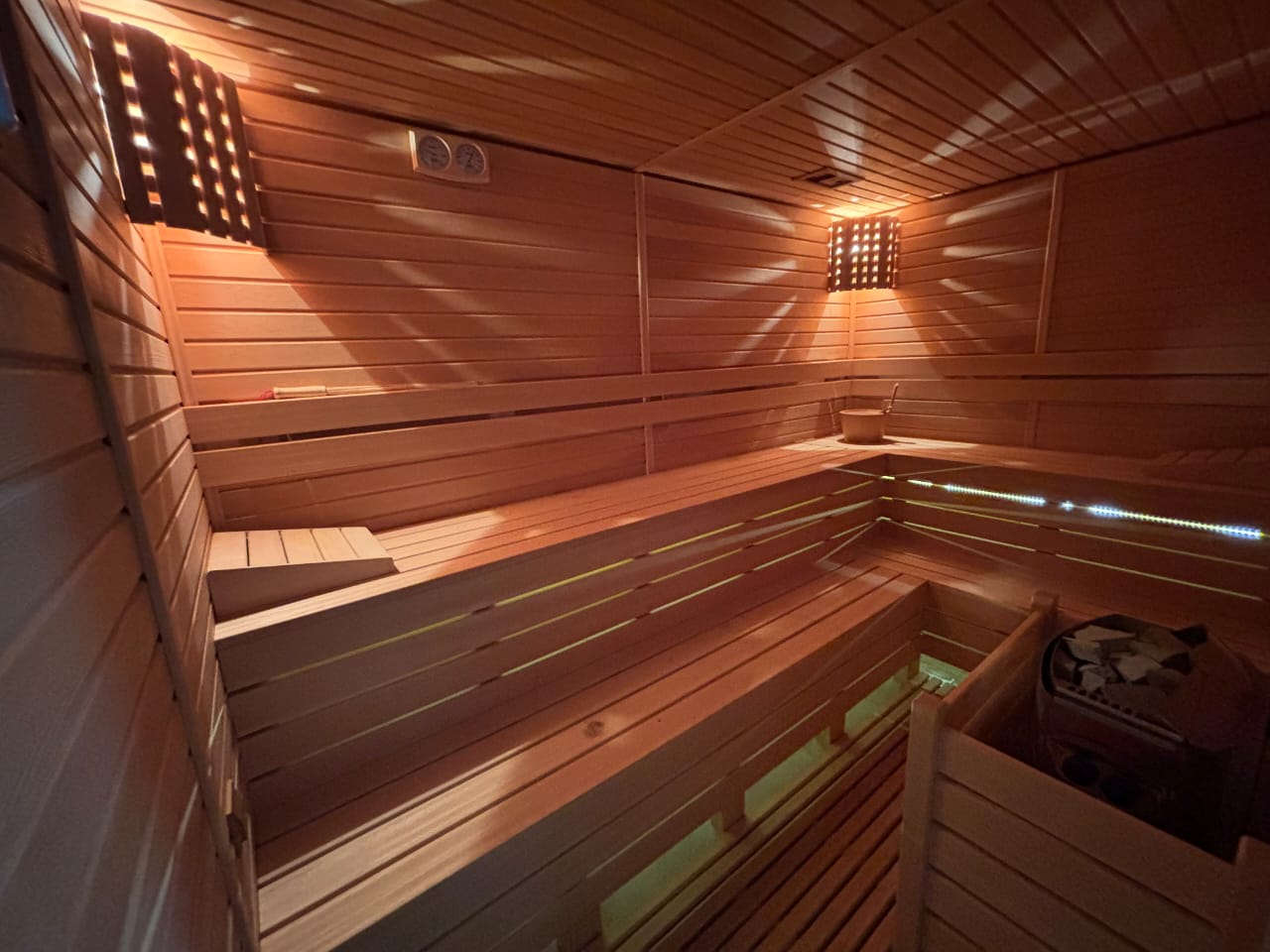 Ahşap raflı sauna, konutun içinde taşlı soba ve raf altı aydınlatmayla