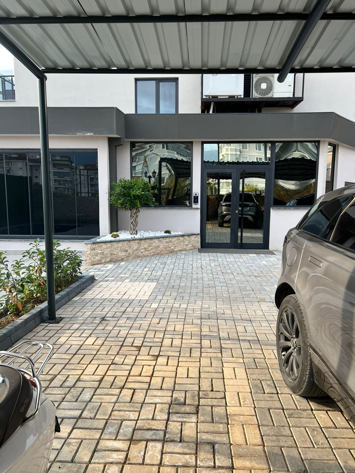 Cam giriş kapıları ve panoramik pencereleri bulunan otopark alanı Oba’daki penthouse’a ait