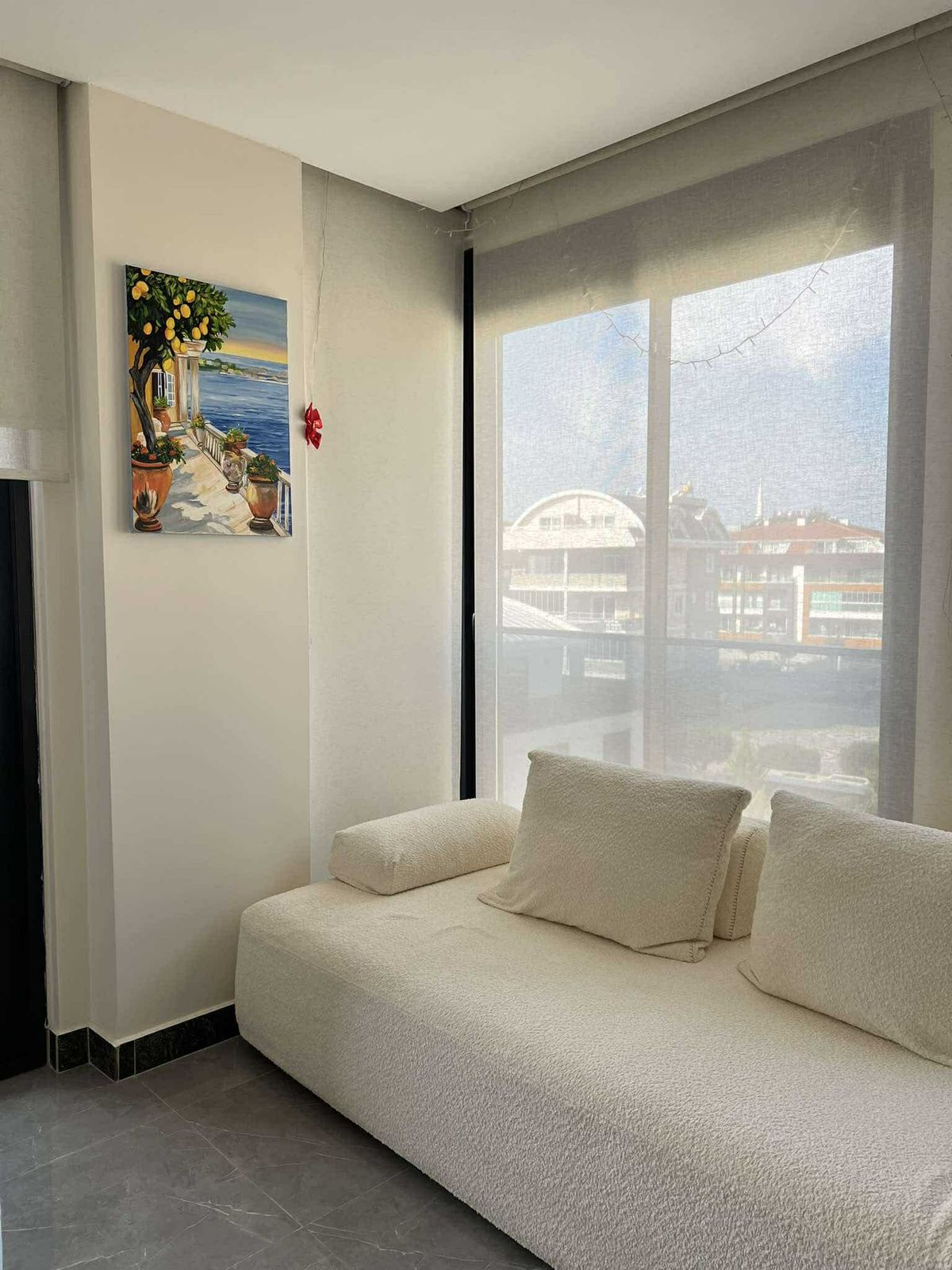 Panoramik köşe pencereli oturma odası, Türkiye’de satılık 2+1 penthouse’un şehir manzarasını sunuyor