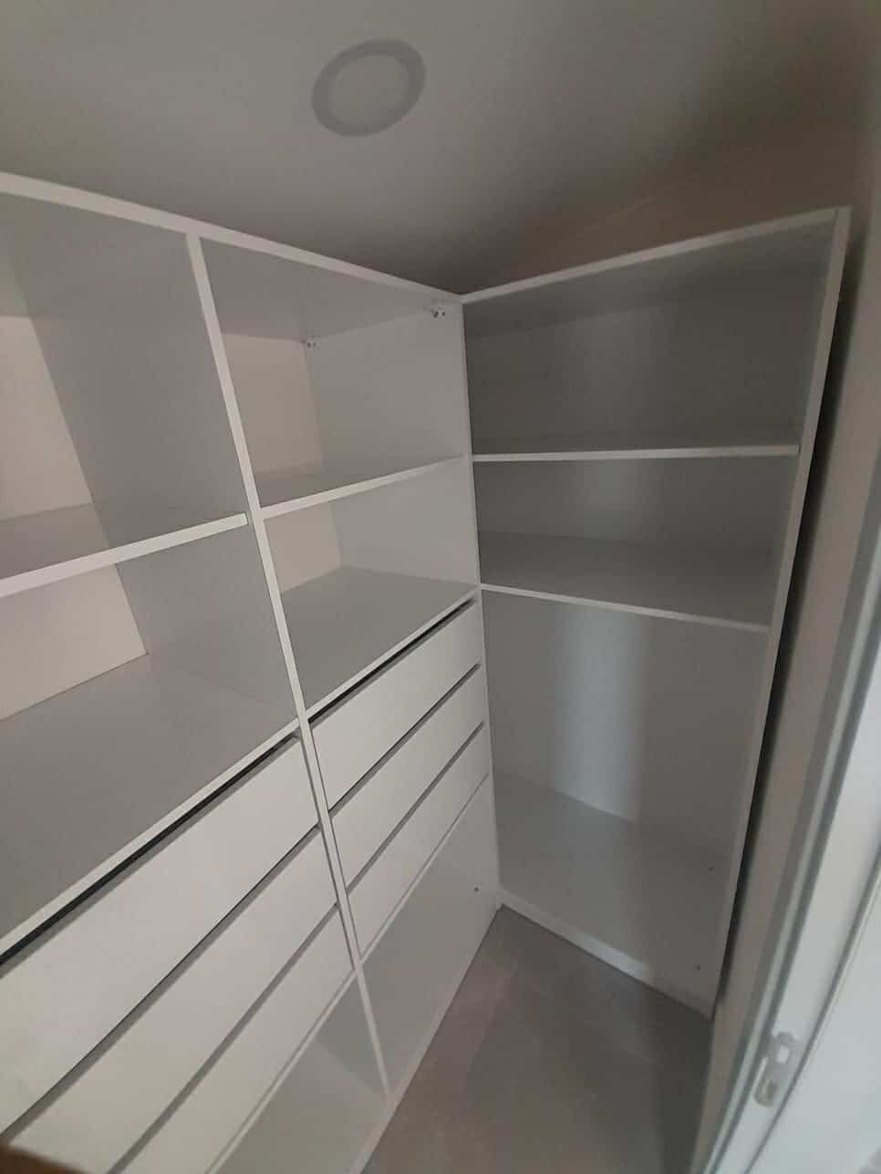 Beyaz gömme dolaplı giyinme odası, Oba’daki rezidansın köşe depolama alanını gösteriyor