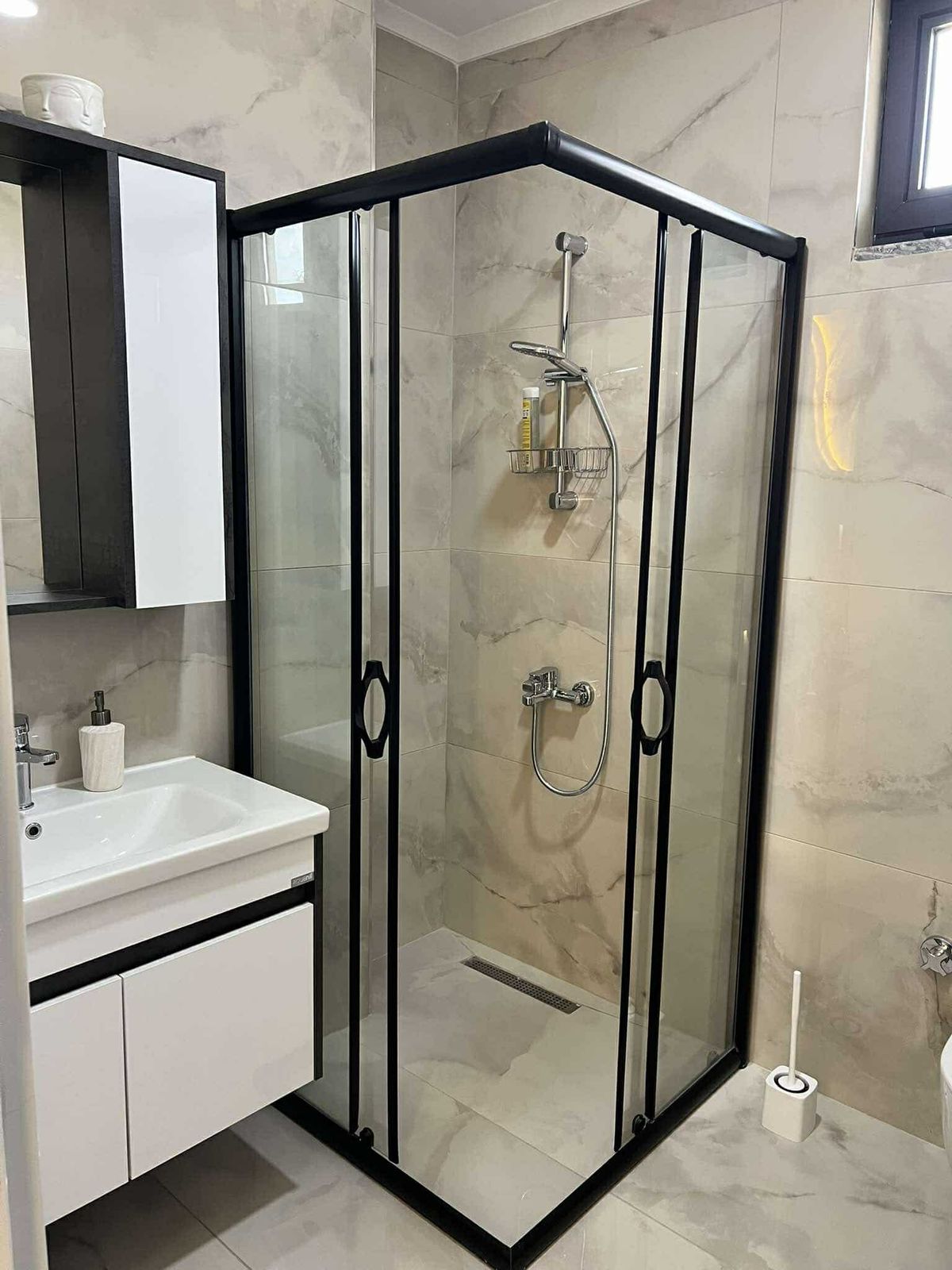 Siyah profilli duş kabinli banyo, Oba’daki penthouse’un mermer desenli alanını gösteriyor