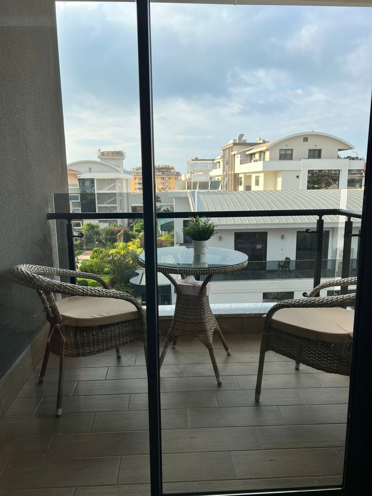 Cam korkuluklu ve iki koltuklu balkon Oba’daki rezidansın şehir ve yeşil alan manzarasına açılıyor