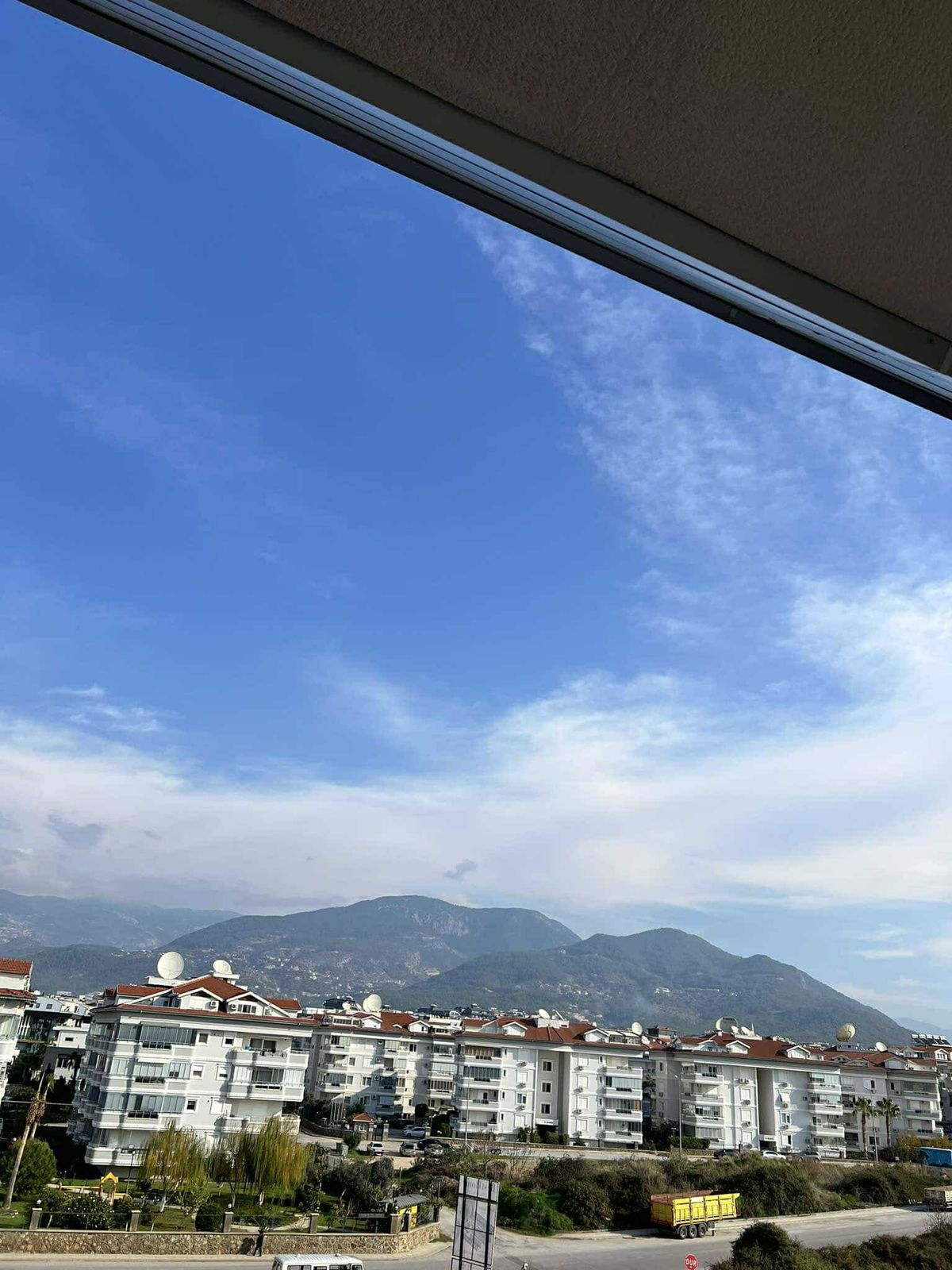 Dağ sırtı ve kırmızı kiremitli şehir evlerini gösteren manzara, satılık penthouse’un çevresini yansıtıyor